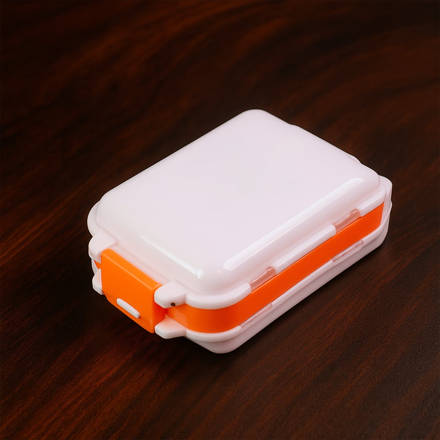 Close-up of secure snap locks on orange dual-sided pill organizer